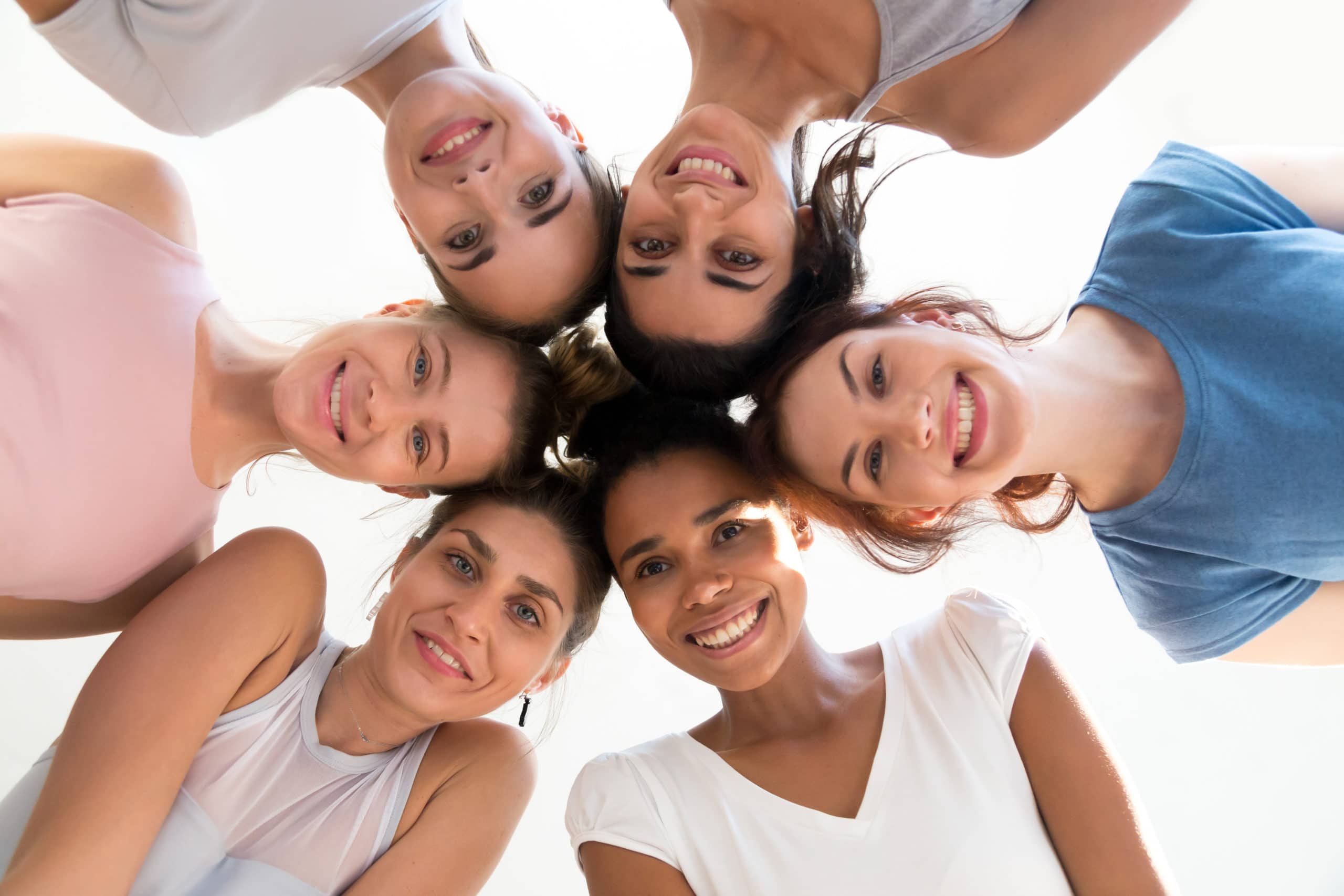 Diverse group of young sporty attractive girls enjoy time togeth Diverse group of sporty attractive girls enjoy time together, smiling people in sportswear after yoga lesson, mixed race female students, happy friends looking at camera. Well being, wellness concept