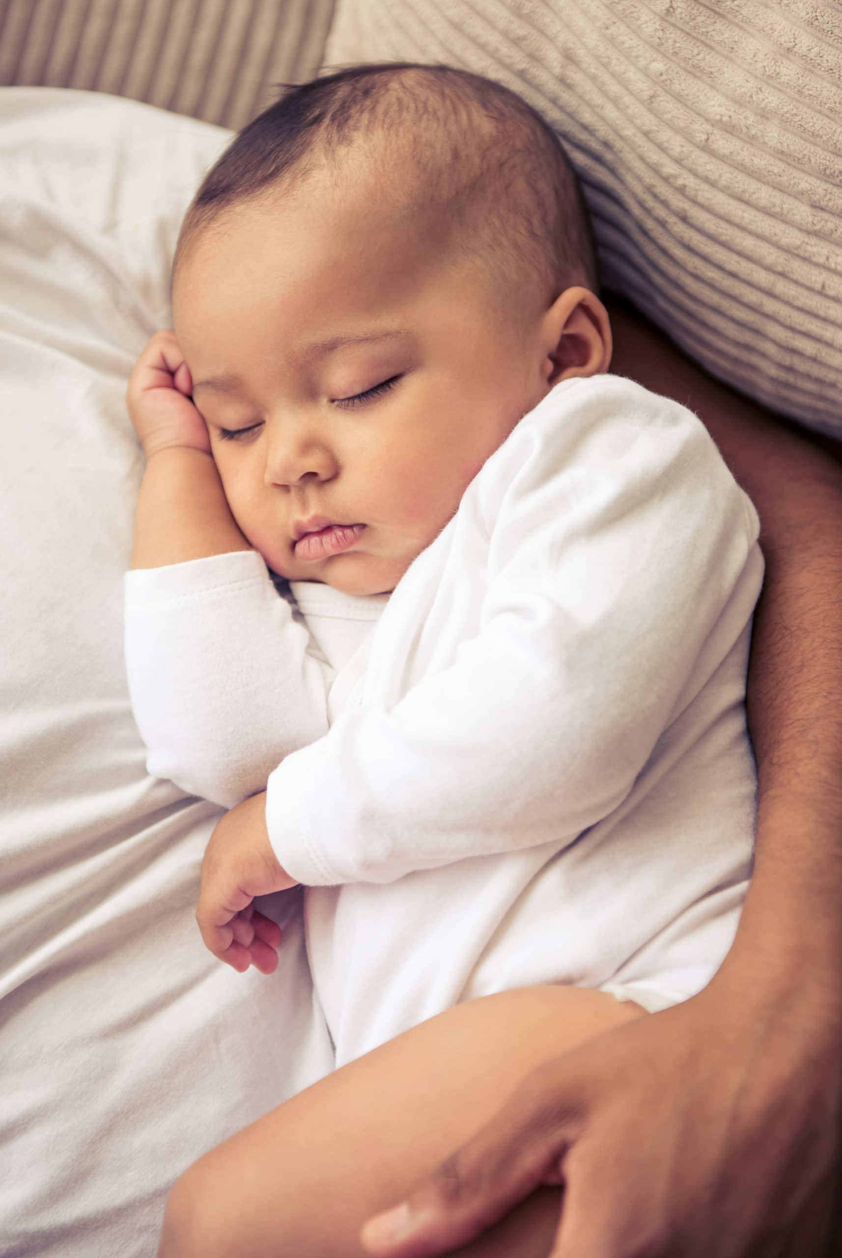 Beautiful little Afro American baby is sleeping in daddy's arms