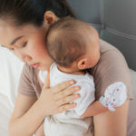 Beautiful mother holding her lovely baby . Infant resting on the shoulder to burp,
