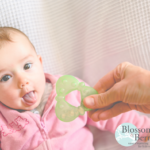 Picture of a baby poking their tongue out and being handed a teething toy