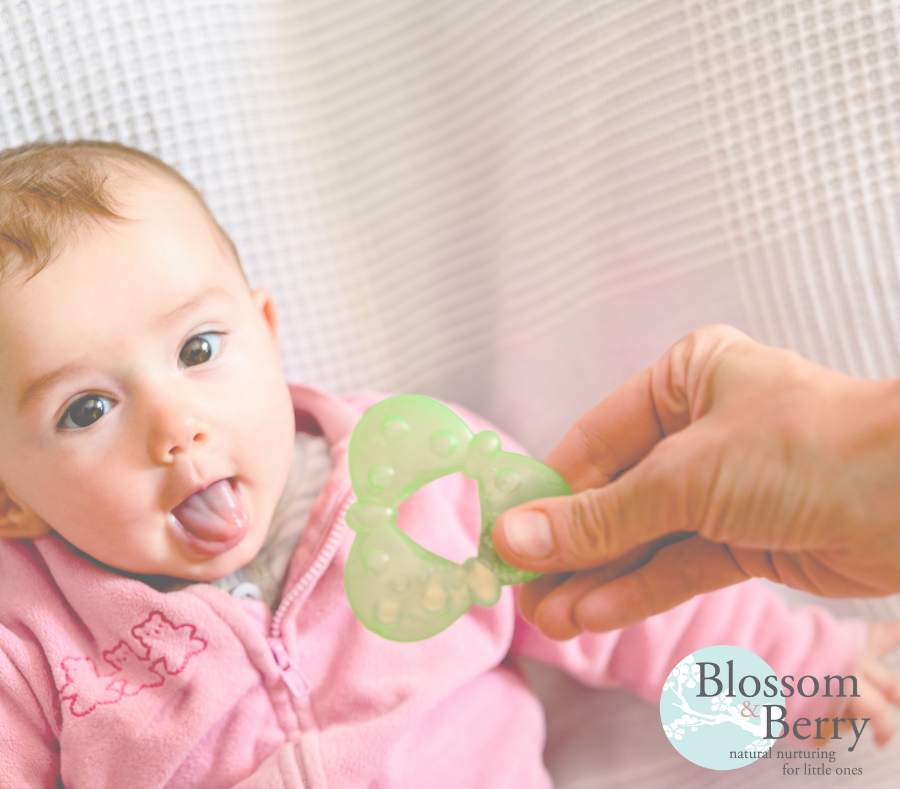 Picture of a baby poking their tongue out and being handed a teething toy