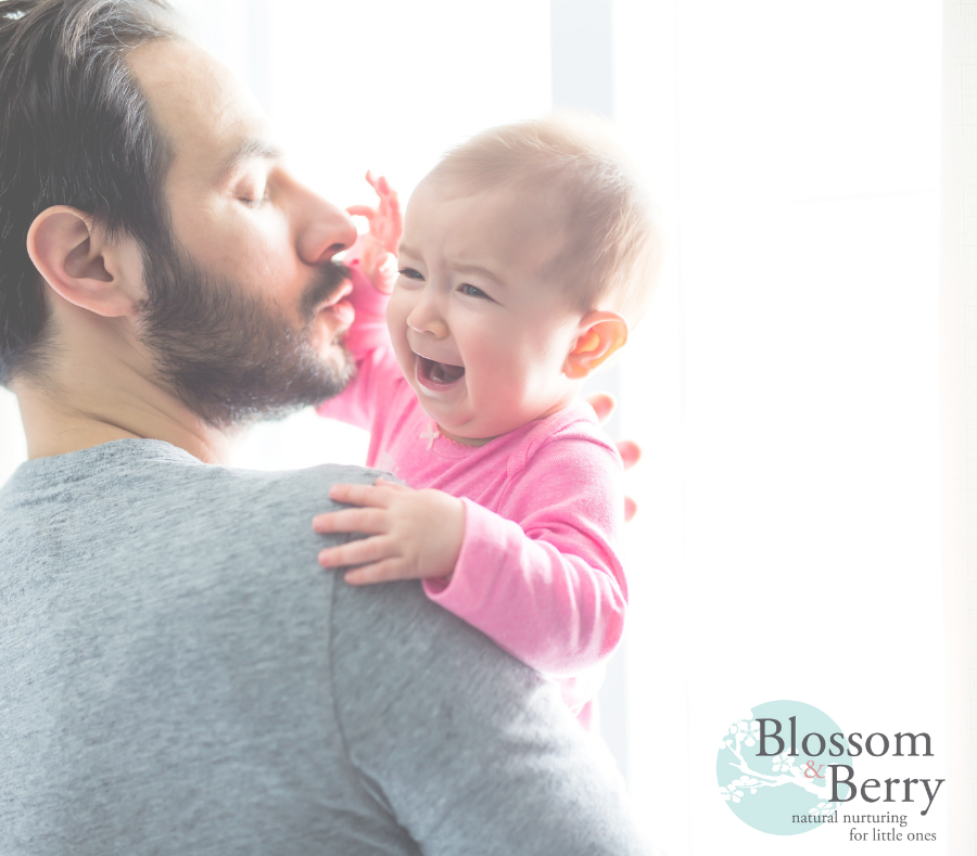 Picture of a man holding a crying baby dressed in pink