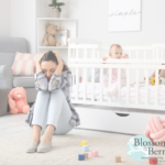 Mum with head in her hands while baby is stood up in their cot in the nursery
