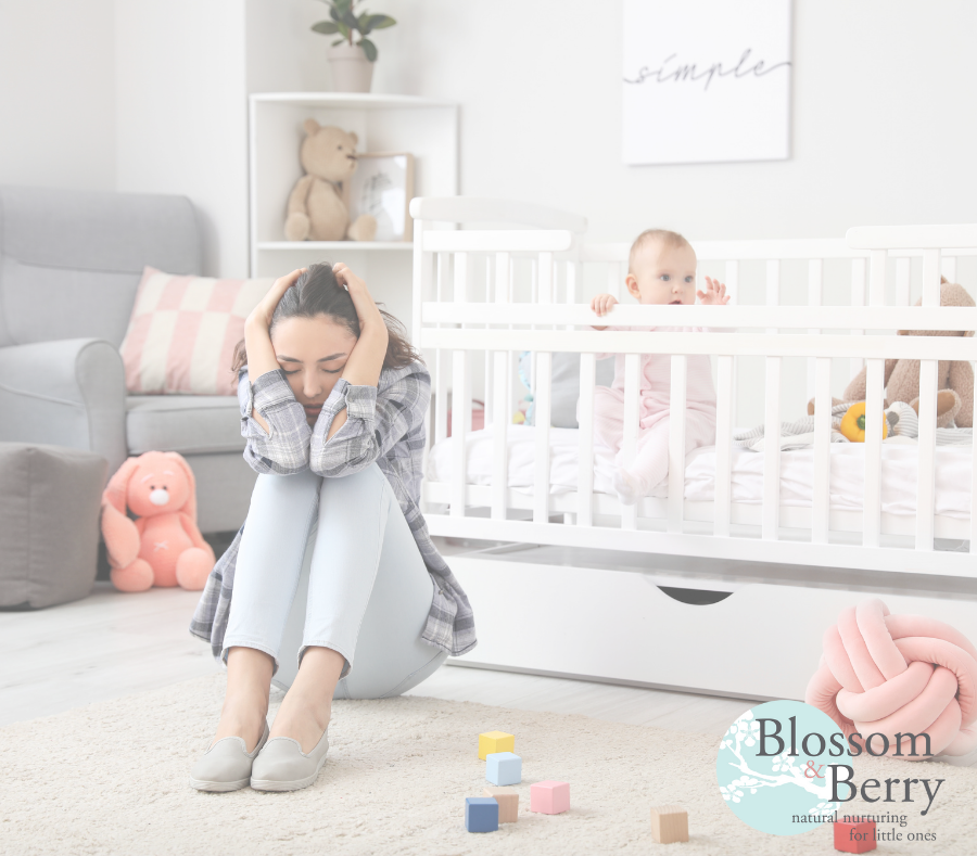 Mum with head in her hands while baby is stood up in their cot in the nursery