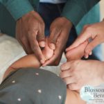 Picture of baby's feet being massaged by two pairs of hands one white and one black