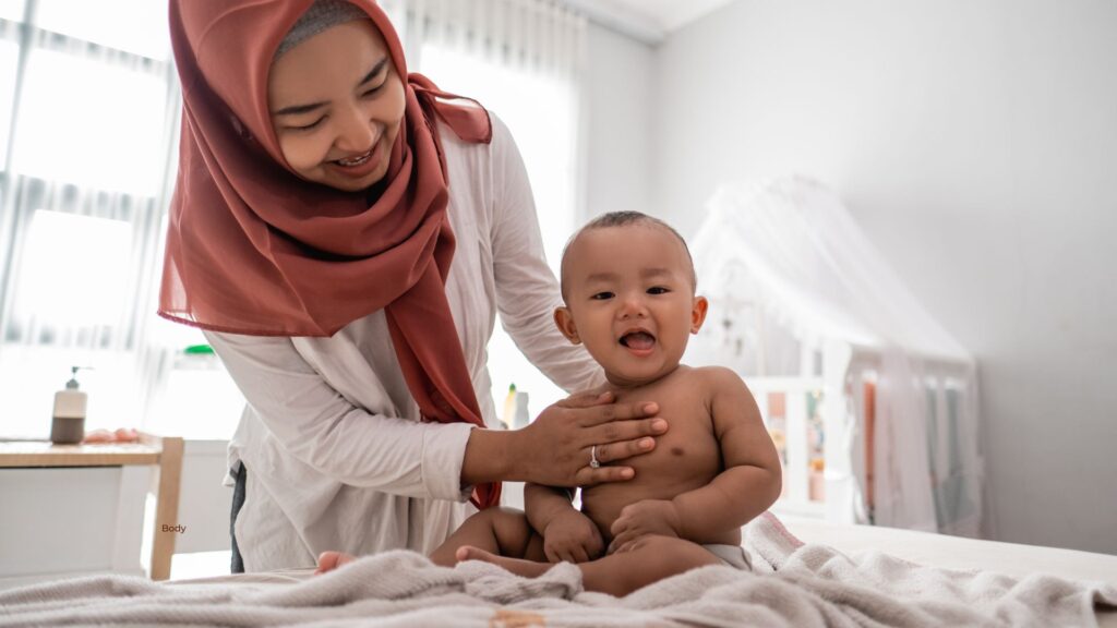 The History of Baby Massage in the Middle East - picture of a lady in a headscarf massing a baby on a bed