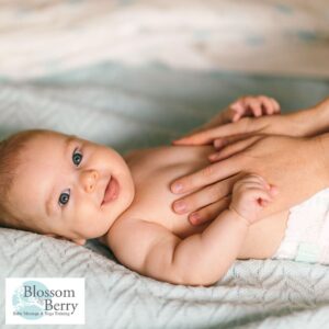 How to Become a Certified Baby Massage Instructor: Step-by-Step Guide - picture of a smiling baby with hands on it's tummy