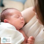 Relieve Trapped Wind in Babies with Massage: Step-by-Step Guide for Parents - picture of a sleeping baby in a womans arms