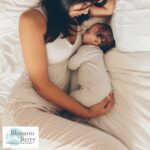 What Are the Biggest Challenges to Parental Wellbeing - picture of a mother lying in bed with her sleeping baby next to her