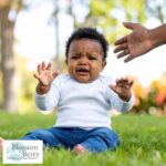 Do Babies Feel Stress? Signs & Ways to Soothe Them - picture of an upset baby sat in a garden